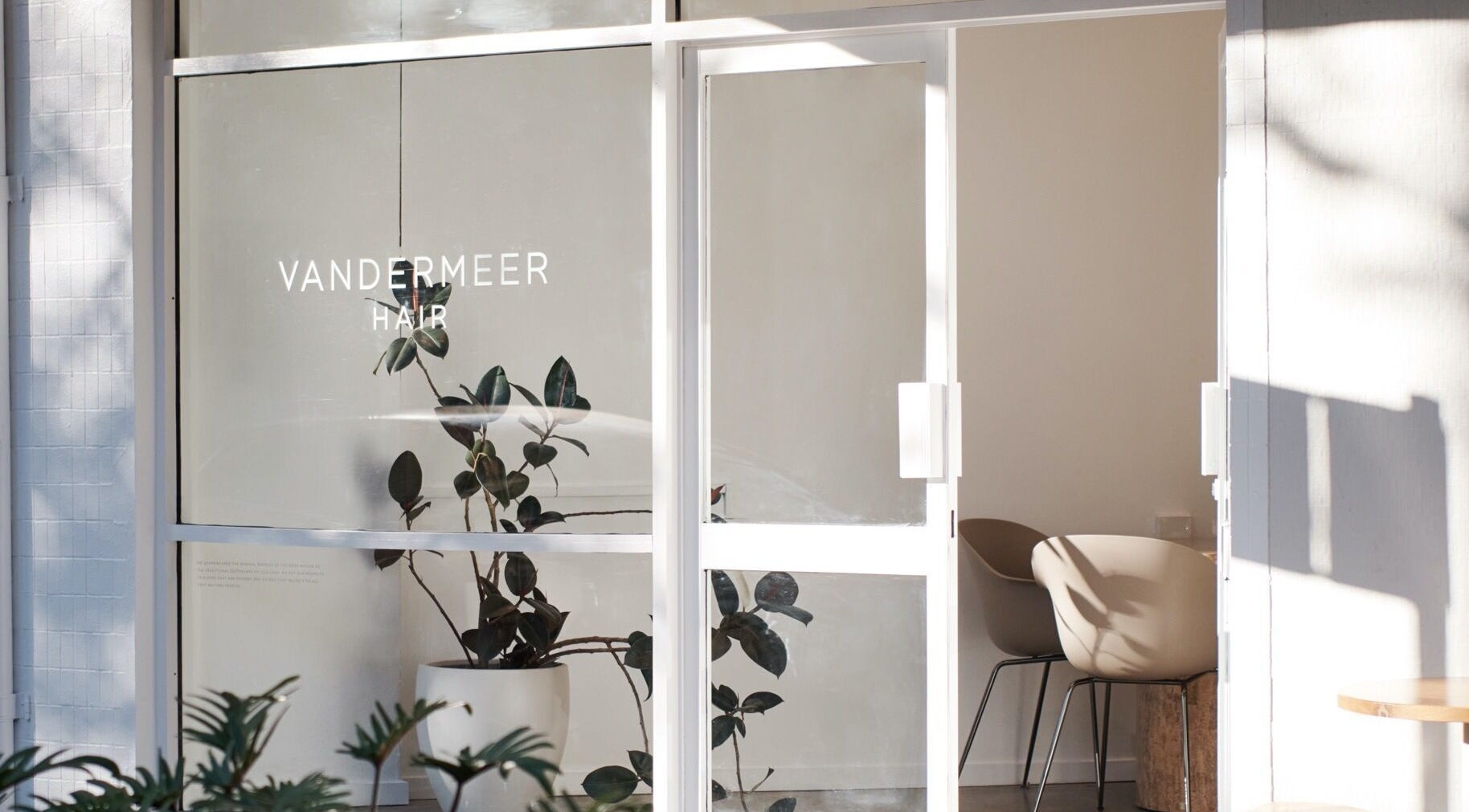 Front entrance of Vandermeer Hair, Surry Hills, New South Wales, AU with glass doors and minimalist decor.
