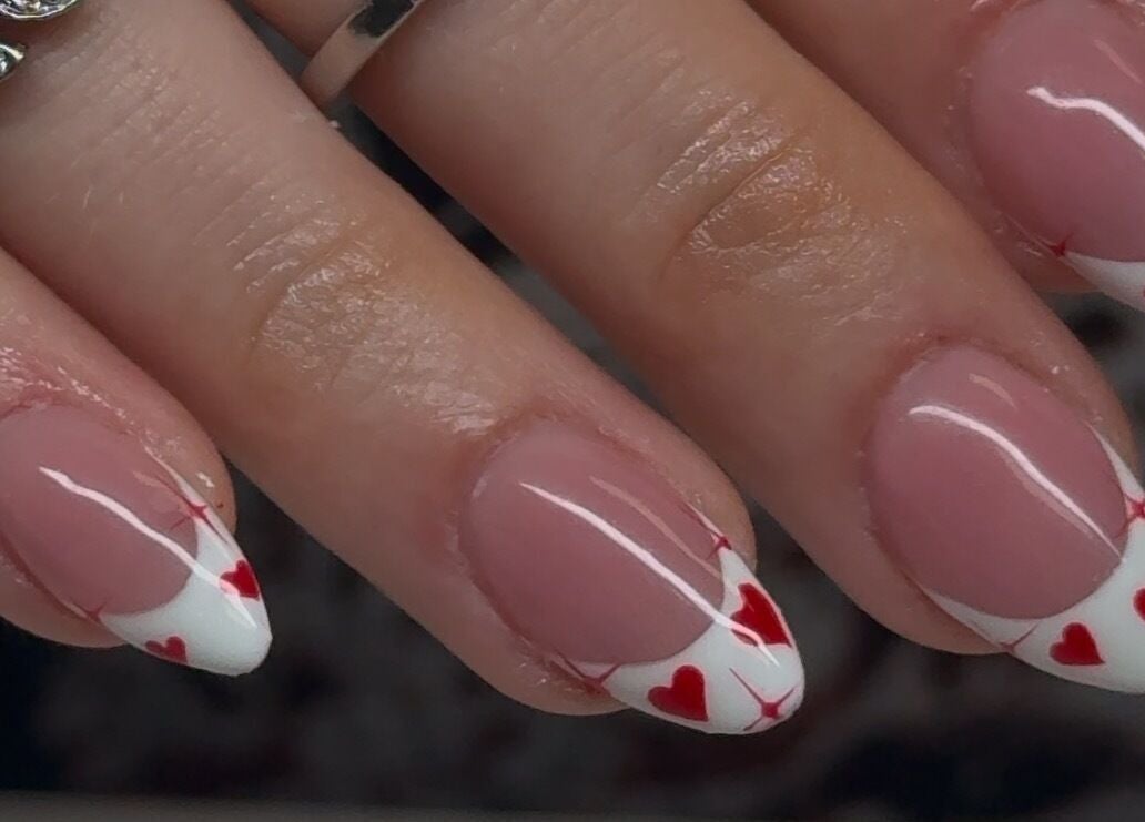 Heart-tipped manicure at Velvet Varnish Lounge, Spring, Texas, US. Elegant nail art with red and white design.