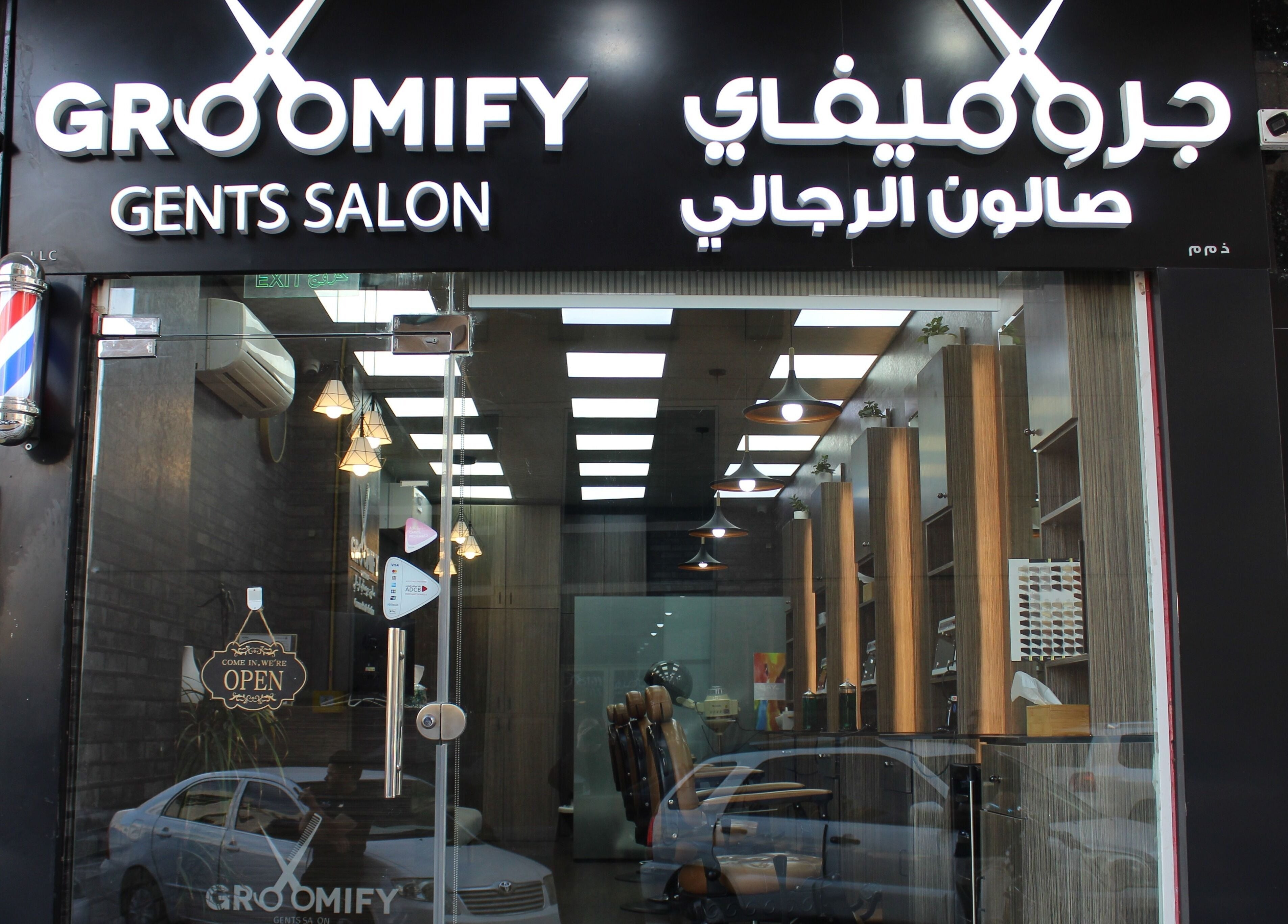 Entrance of Groomify Gents Salon in Abu Dhabi, AE, showcasing modern glass and welcoming decor.