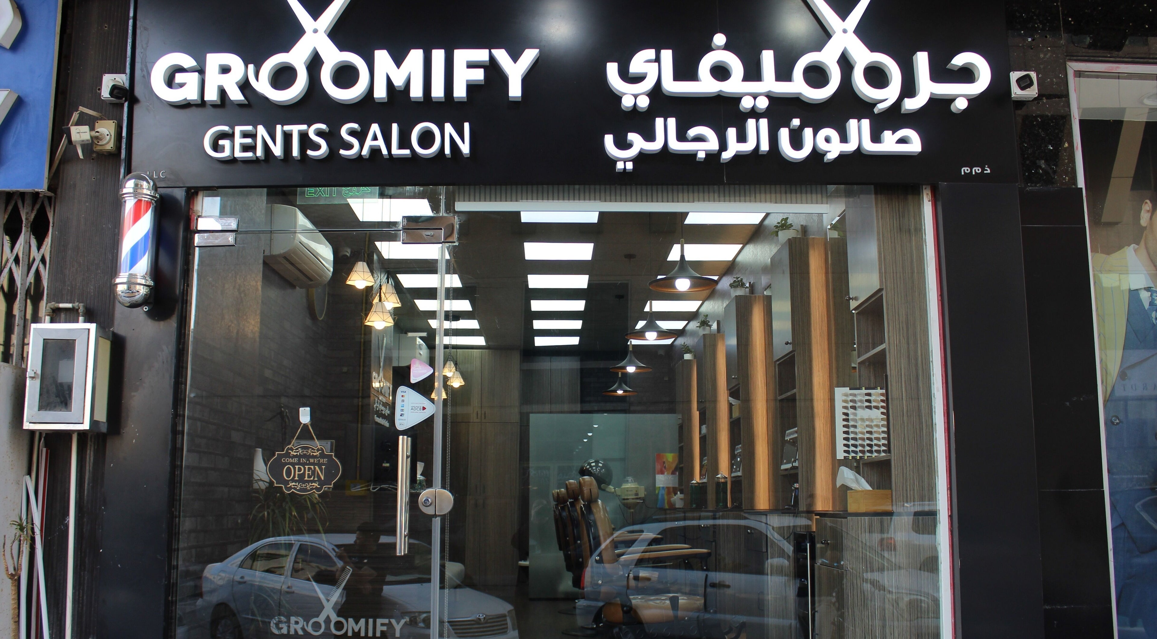Entrance of Groomify Gents Salon in Abu Dhabi, AE, showcasing modern glass and welcoming decor.