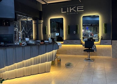 Interior moderno de Like Barbería en San Juan, AR, mostrando espejos iluminados y estación de barbería.