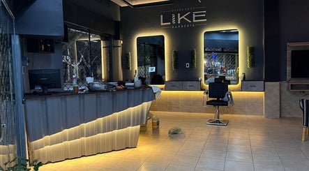 Interior moderno de Like Barbería en San Juan, AR, mostrando espejos iluminados y estación de barbería.