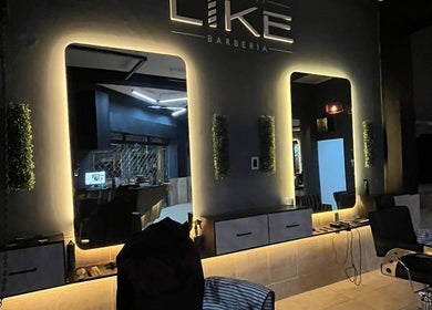 Interior elegante de Like Barbería en San Juan, AR, con espejos iluminados y sillas de peluquero modernas.