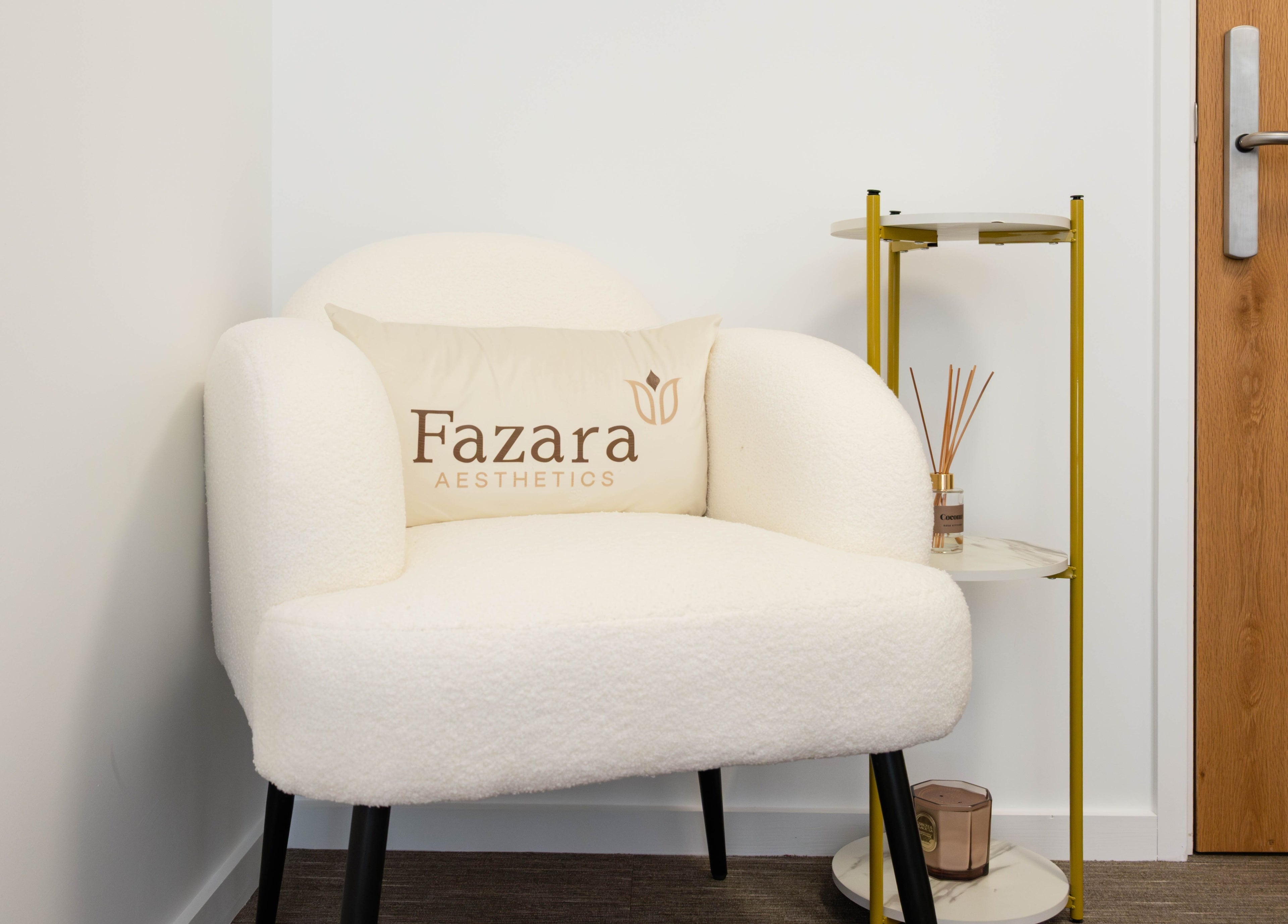 Plush chair with Fazara Aesthetics pillow in relaxing corner at Fazara Aesthetics, London E14 9DQ, England, GB.