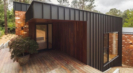 Stylish wooden and brick exterior at Hairbykendallk, Melbourne, Victoria, AU, surrounded by lush greenery.