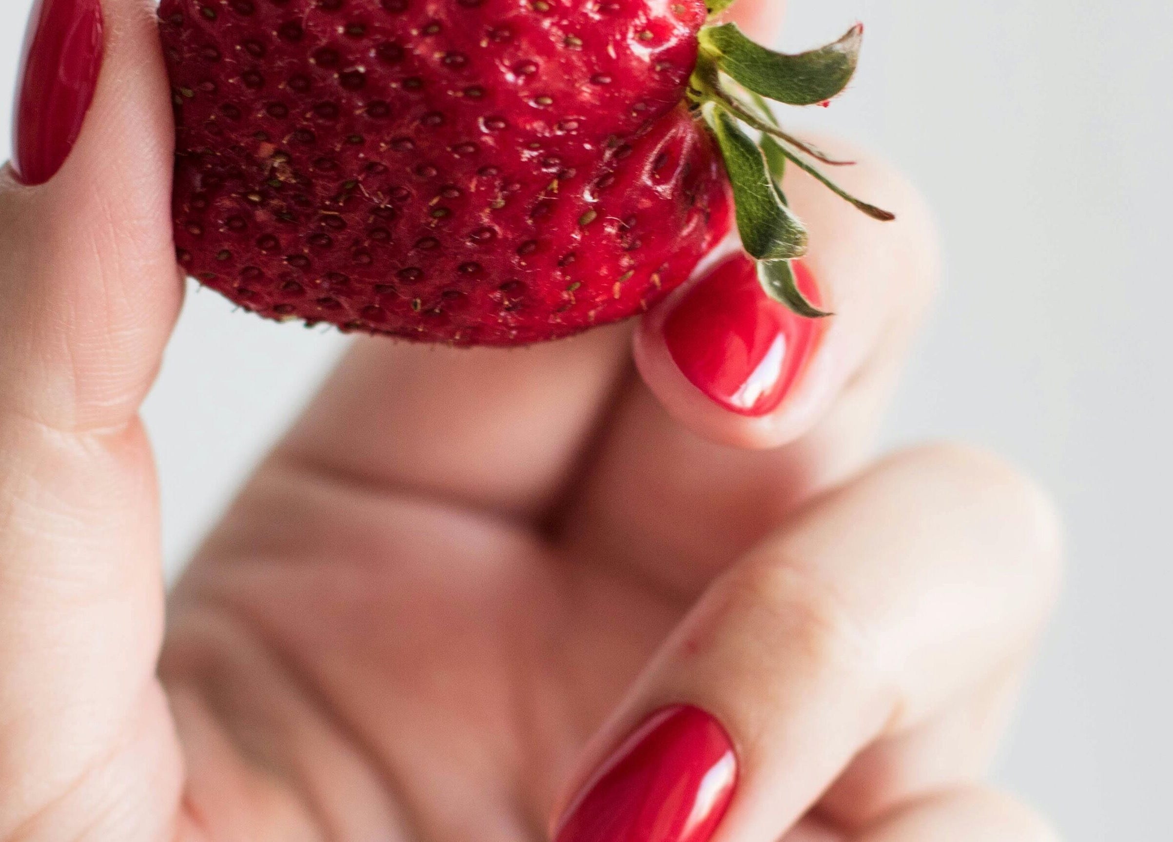 Μανικιούρ φράουλα στο Manicute Aesthetics, Παλαιό Φάληρο, GR. Κομψά κόκκινα νύχια αγκαλιάζουν μια φράουλα.