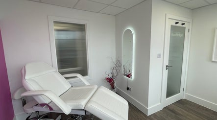 A pristine treatment room at Pure Aesthetics by Tara, London, England, with a white chair and ambient decor.