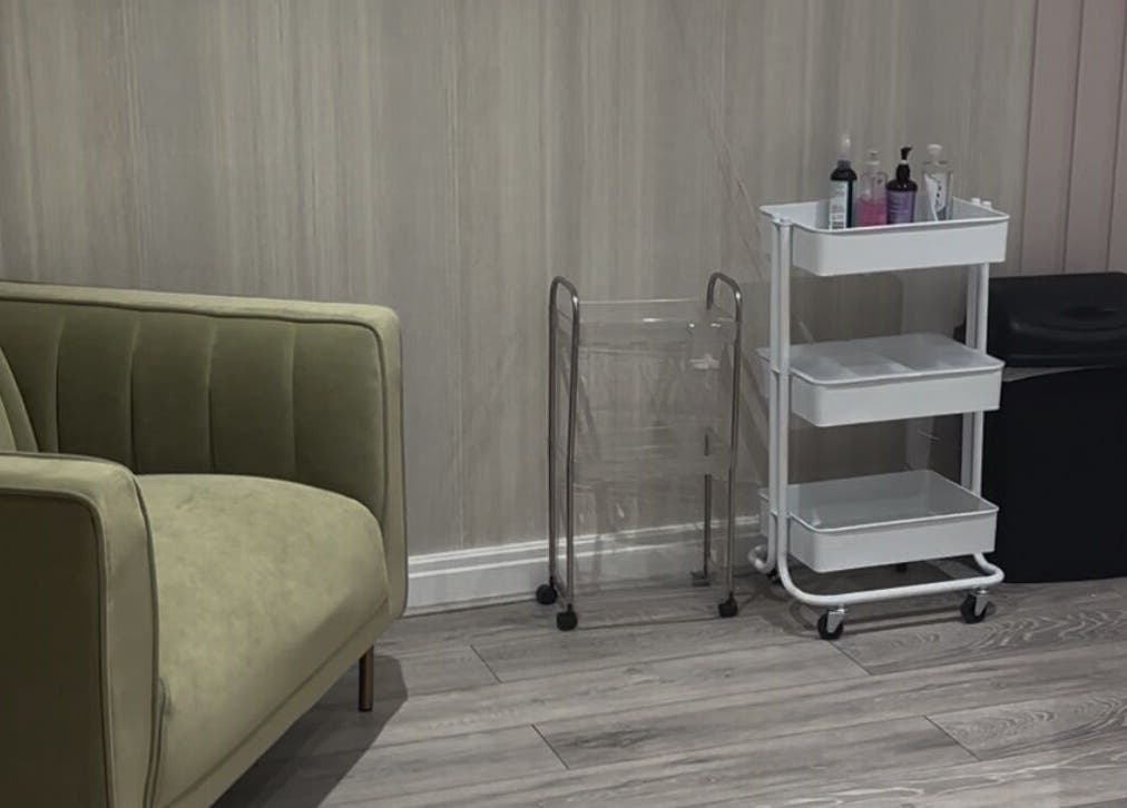 Relaxing corner at Sculpted Cosmetics Ltd, Orpington, England, GB, featuring a stylish green sofa and sleek cart.