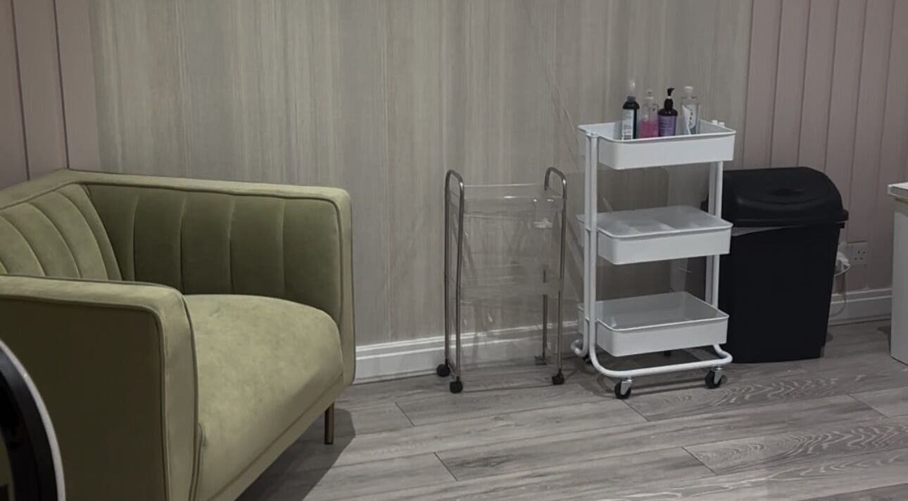 Relaxing corner at Sculpted Cosmetics Ltd, Orpington, England, GB, featuring a stylish green sofa and sleek cart.