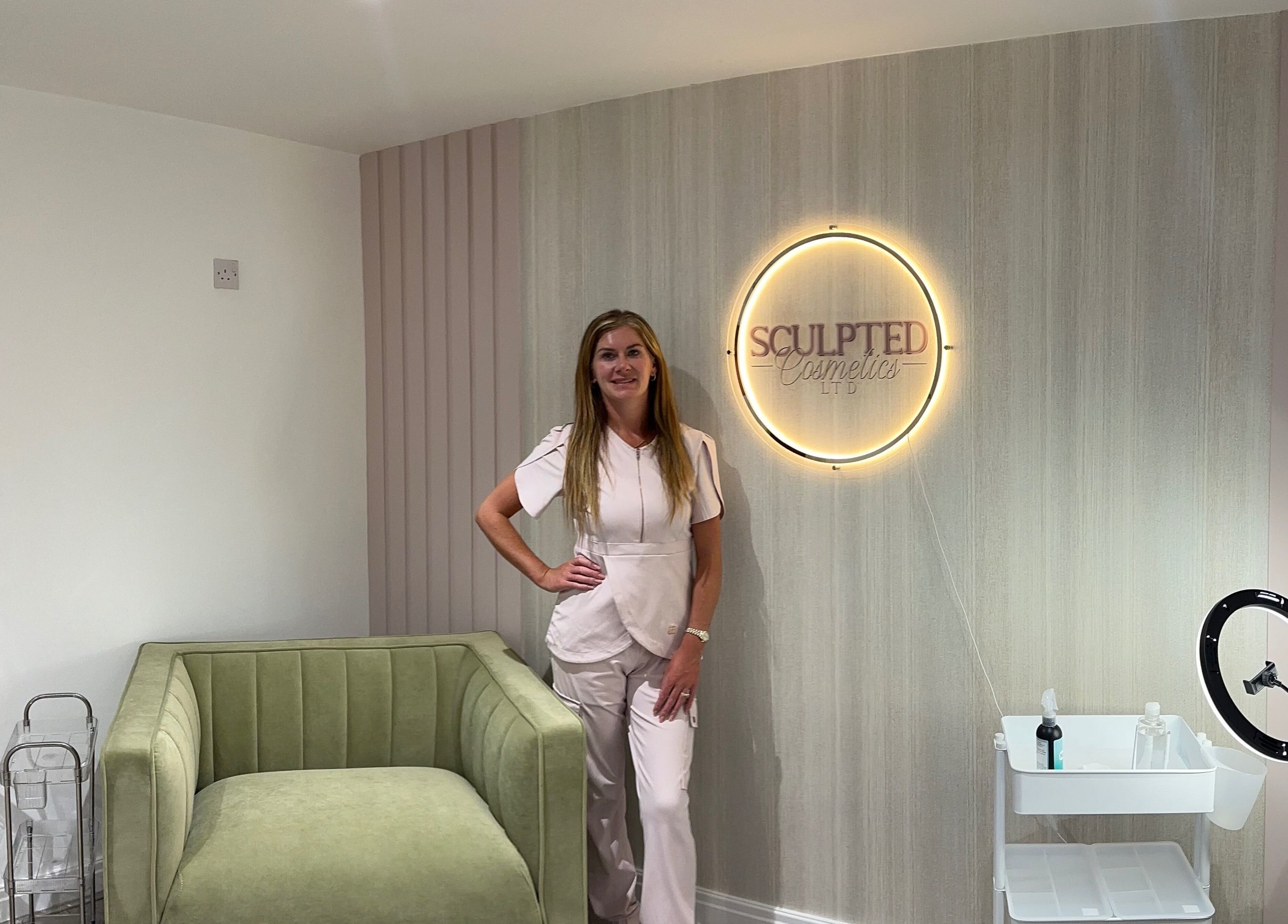 Elegant room at Sculpted Cosmetics Ltd, Orpington, England, GB featuring a comfortable sofa and glowing wall sign.
