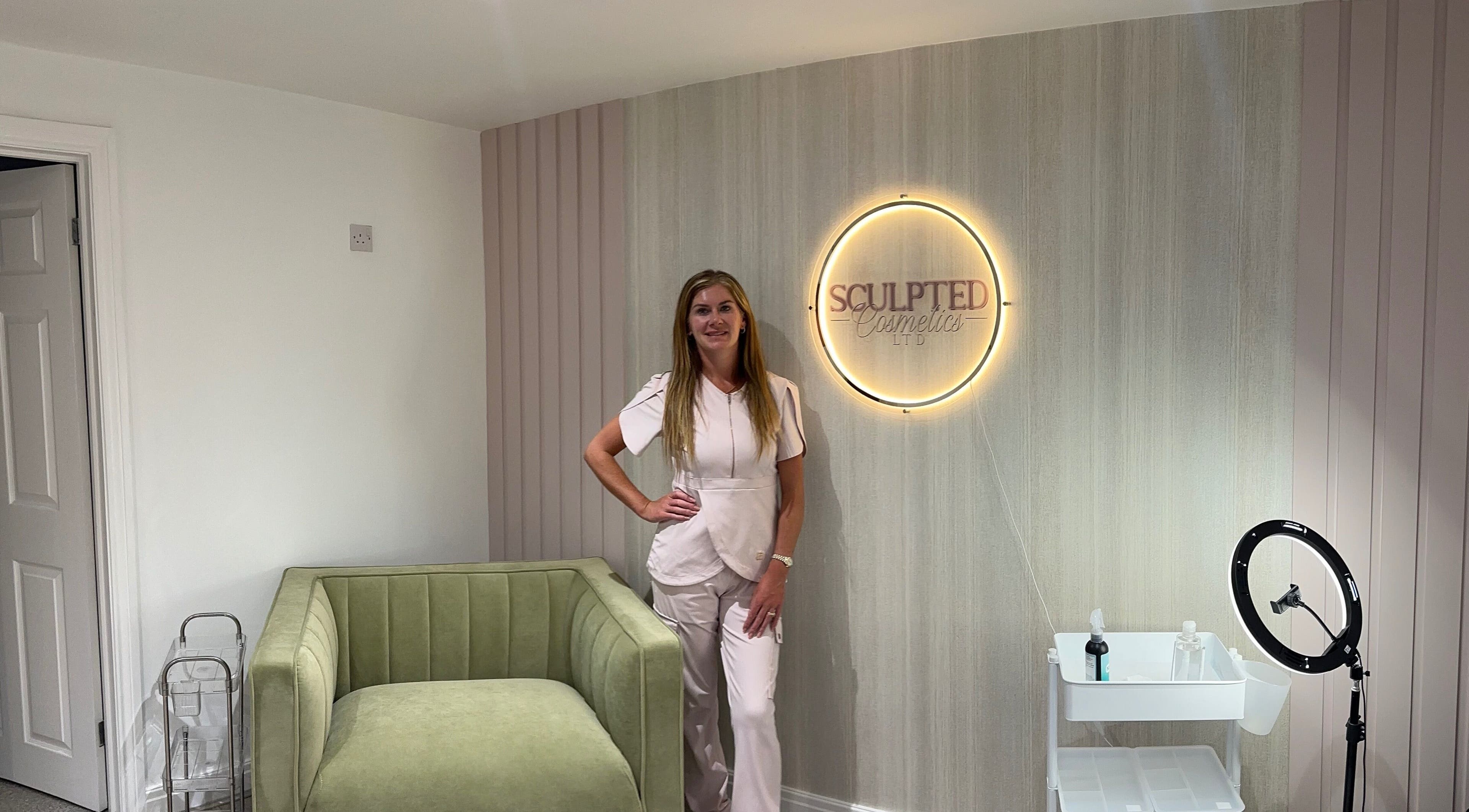 Elegant room at Sculpted Cosmetics Ltd, Orpington, England, GB featuring a comfortable sofa and glowing wall sign.