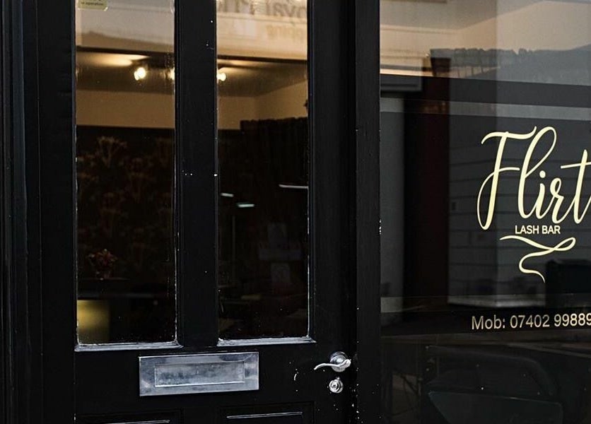 Entrance of Flirt Lash & Brow Bar in Leamington Spa, England, GB, showcasing elegant signage and welcoming doorway.