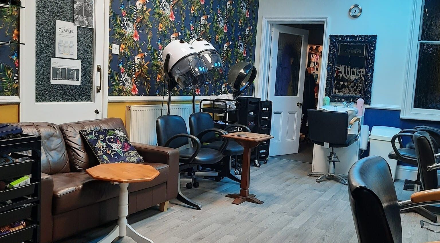 Trendy interior of Eclipse Hair Studio in Stafford, England, GB, featuring modern chairs and a floral wall design.