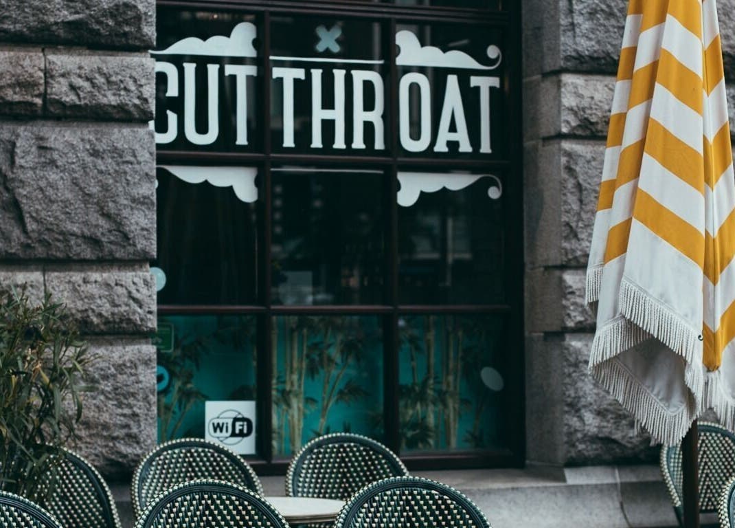 Outdoor seating at Cut Throat - Beursplein, Amsterdam, Noord-Holland, NL with visible signage.