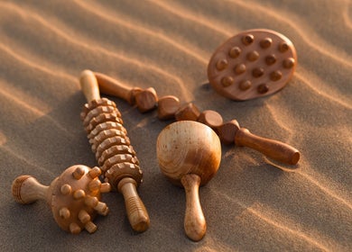 Outils de massage en bois chez Metamorphe Massage, Lattes, Occitanie, FR, sur du sable apaisant.