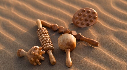 Outils de massage en bois chez Metamorphe Massage, Lattes, Occitanie, FR, sur du sable apaisant.
