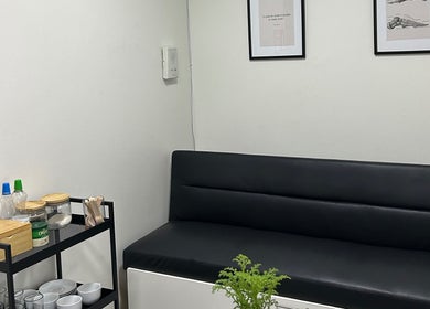 Sala de espera moderna en Podovita, La Reina, Región Metropolitana, CL, con sofá negro y decoración minimalista.