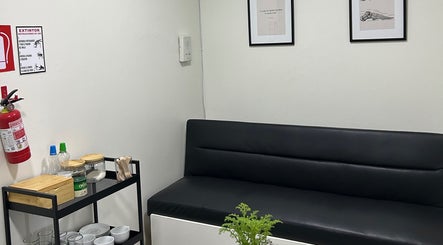 Sala de espera moderna en Podovita, La Reina, Región Metropolitana, CL, con sofá negro y decoración minimalista.