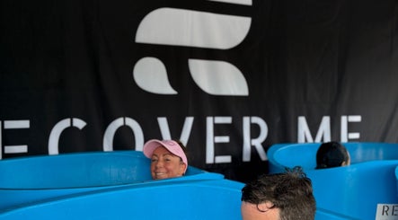 People in blue tubs relaxing at Fourtress 2025, Auckland, Auckland, NZ. Wellness experience with branded backdrop.