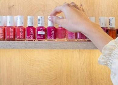 A hand selects vibrant nail polish at Al-Kheesa Branch, Doha, Al Daayen, QA.