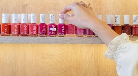 A hand selects vibrant nail polish at Al-Kheesa Branch, Doha, Al Daayen, QA.