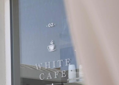 White cafe sign on window at Al-Kheesa Branch, Doha, Al Daayen, QA, offering stylish ambiance.
