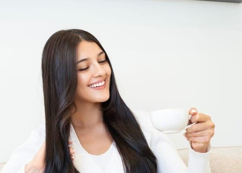 Smiling woman enjoying tea at Al-Kheesa Branch, Doha, Al Daayen, QA's beauty and wellness venue.