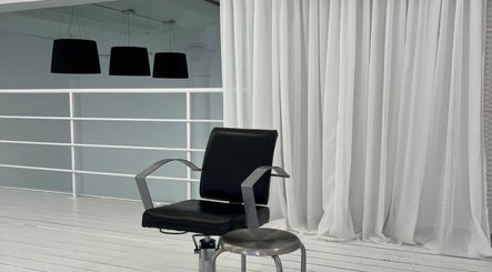 Sleek black styling chair at Melt Hair Studio by Aline Monsani, Barcelona, Catalunya, ES with stylish white drapes.