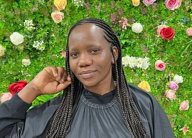 Cliente satisfeita com tranças em Missbala's Beauty Hair Braids Salon, Montijo, Setúbal, PT, em fundo florido.