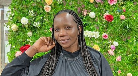 Cliente satisfeita com tranças em Missbala's Beauty Hair Braids Salon, Montijo, Setúbal, PT, em fundo florido.