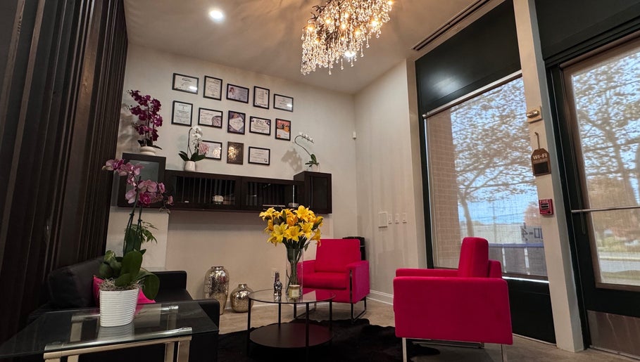 Elegant lounge at Beauty Spot by Elena, North Bethesda, Maryland, US with vibrant pink seating and a chandelier.