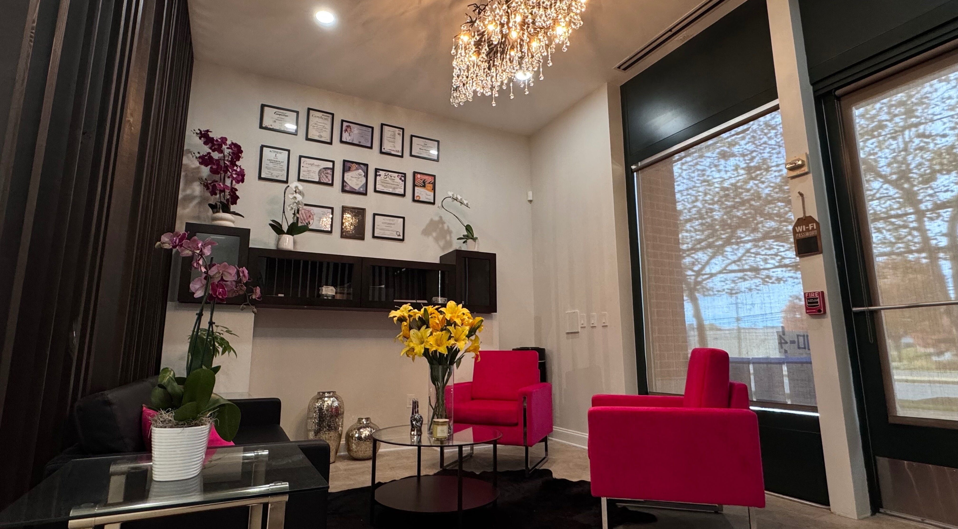 Elegant lounge at Beauty Spot by Elena, North Bethesda, Maryland, US with vibrant pink seating and a chandelier.