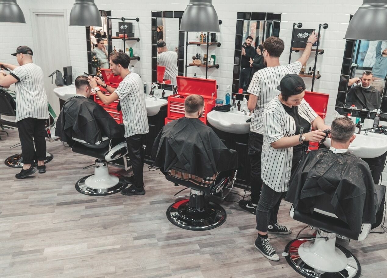 Interno del Little Italy Barbershop a Voghera - Cc Montebello, Lombardia. Ambiente moderno con clienti e barbieri.
