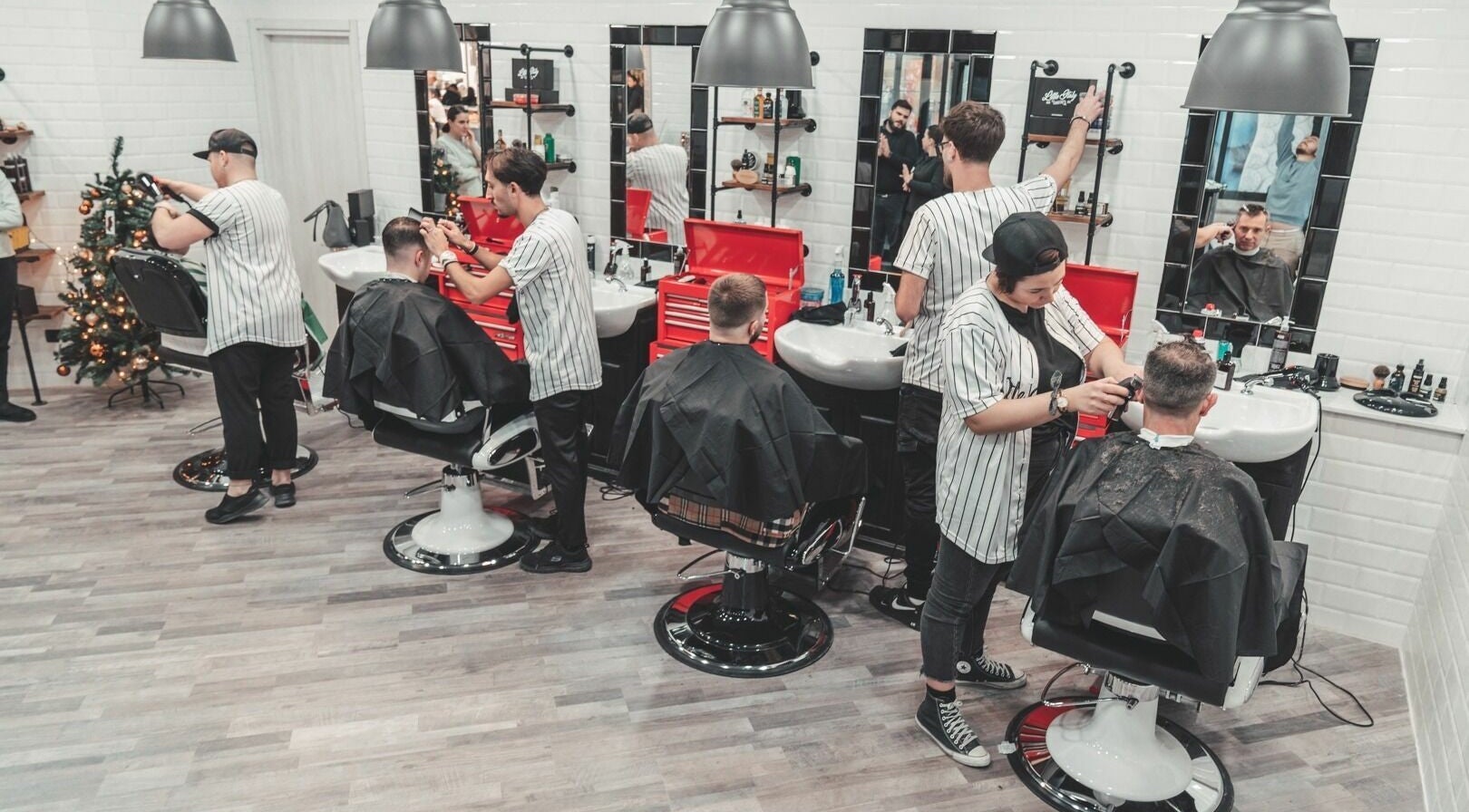 Interno del Little Italy Barbershop a Voghera - Cc Montebello, Lombardia. Ambiente moderno con clienti e barbieri.