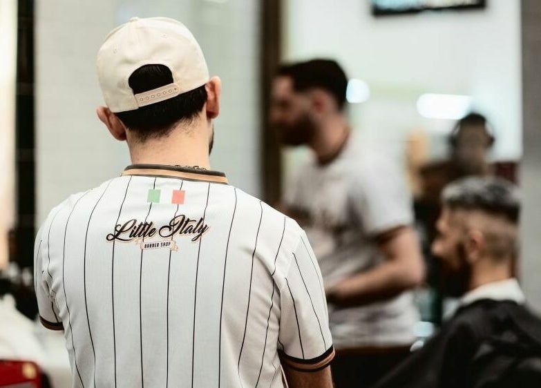 Interno di Little Italy Barbershop a Pavia - Cc Carrefour, Pavia, Lombardia, IT. Uomo con maglietta strisce.