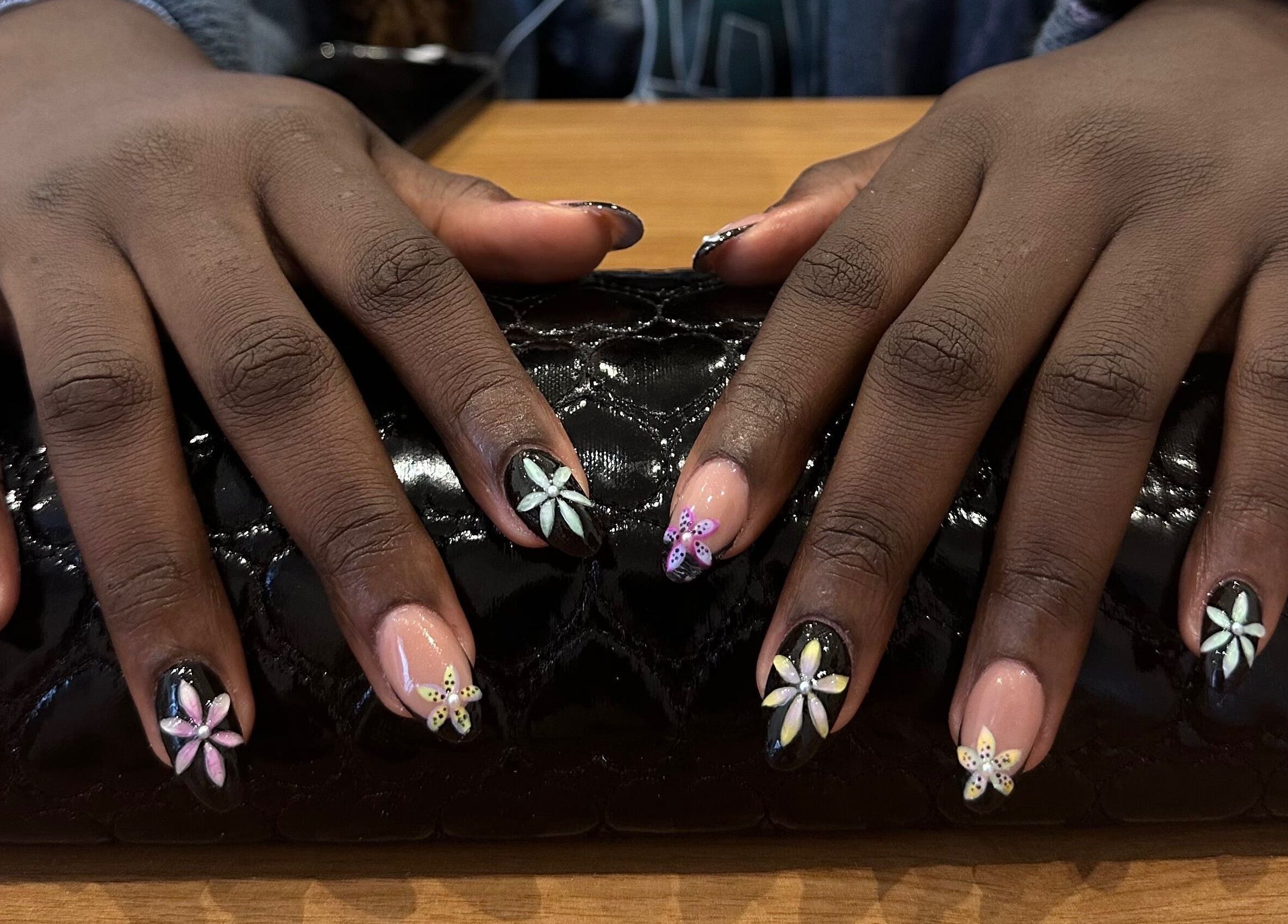 Detailed floral nail art at Studio Rae, Aberdeen, Scotland, GB, showcasing intricate designs on a black clutch.