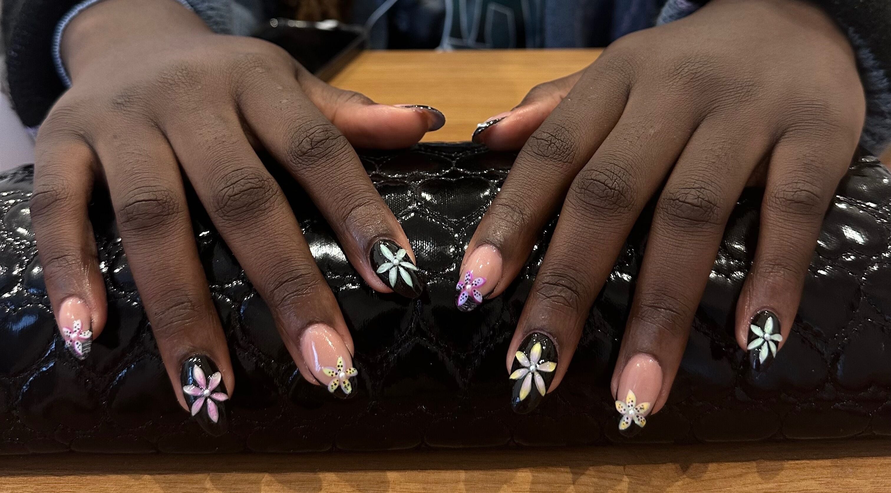 Detailed floral nail art at Studio Rae, Aberdeen, Scotland, GB, showcasing intricate designs on a black clutch.