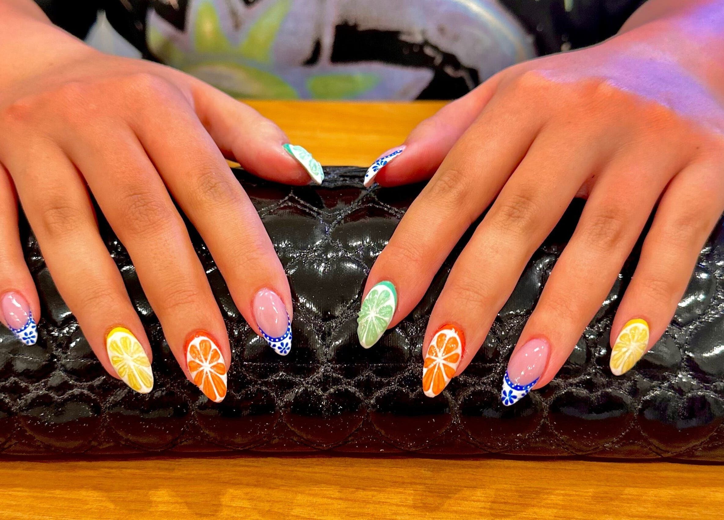 Vibrant citrus nail art at Studio Rae in Aberdeen, Scotland, GB on a glossy black clutch.