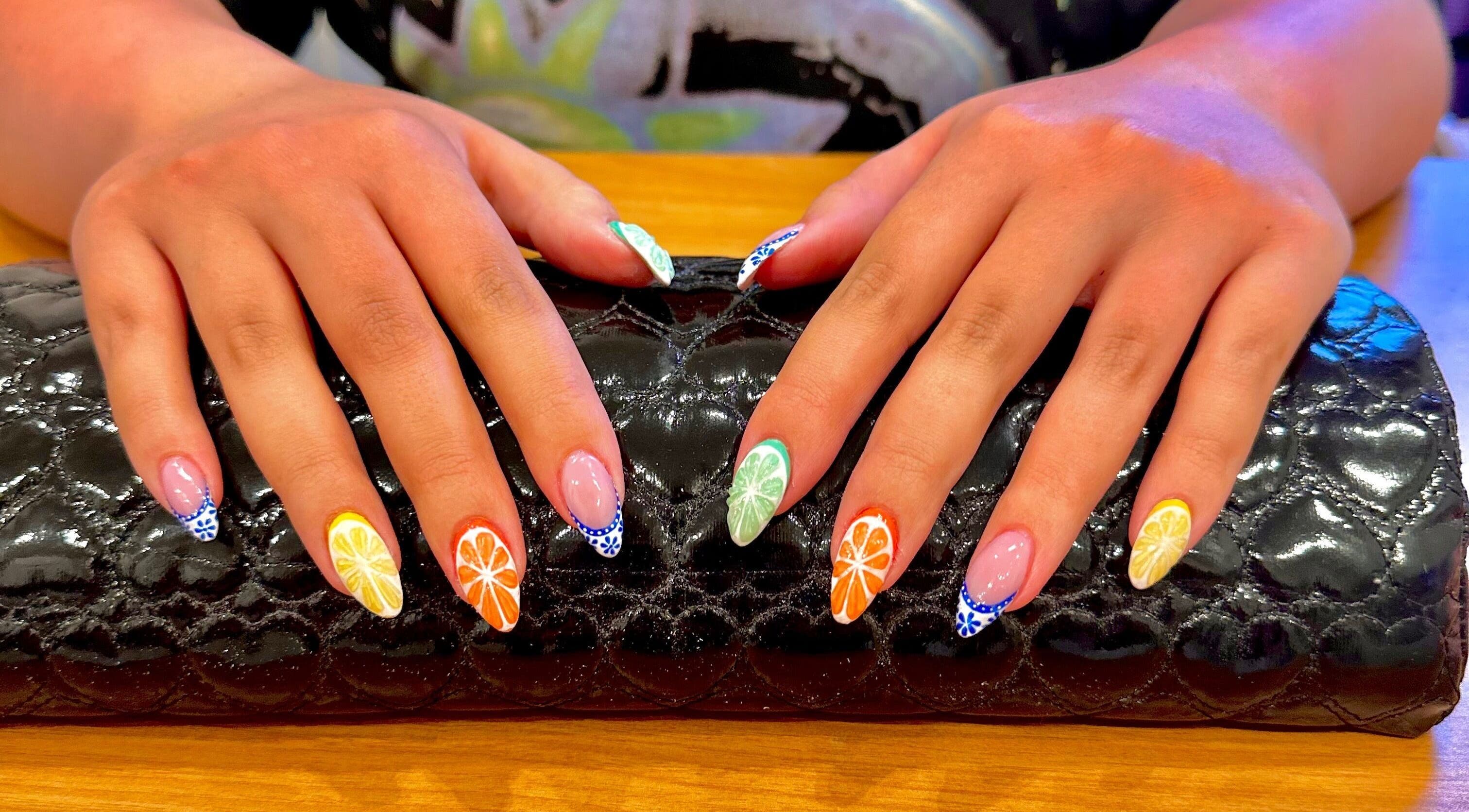 Vibrant citrus nail art at Studio Rae in Aberdeen, Scotland, GB on a glossy black clutch.