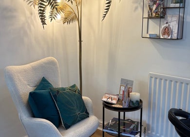 Cozy corner at The Vine Hair by Georgia in Solihull, England, GB, featuring a plush chair and reading materials.