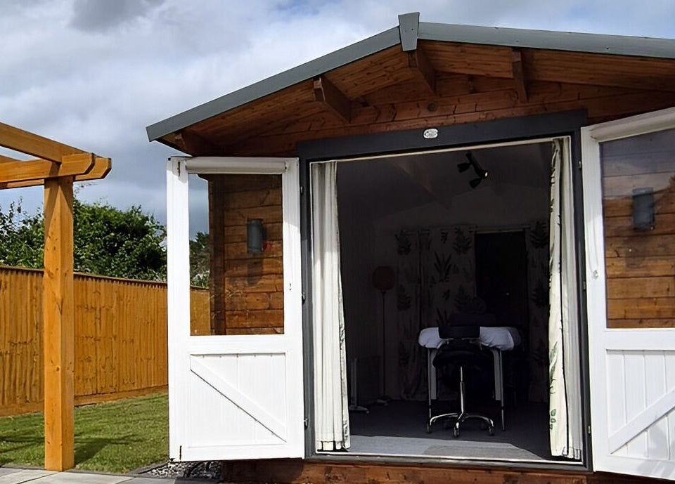 Charming outdoor cabin at Calathea Holistic Health and Wellness in Wimborne, England, GB, with open doors.