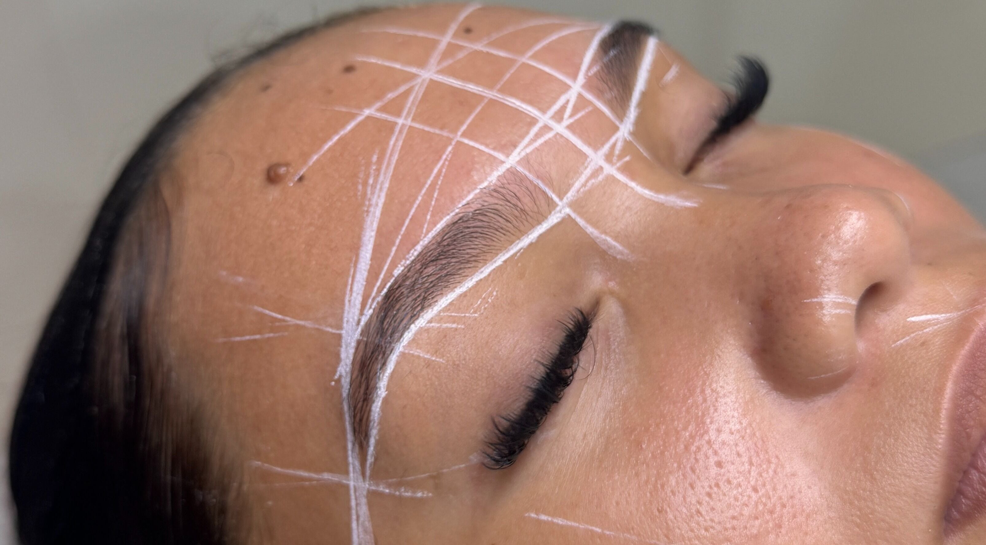 Precision brow shaping at Santoriam, Willemstad, Curaçao, CW showcasing detailed white guide lines.