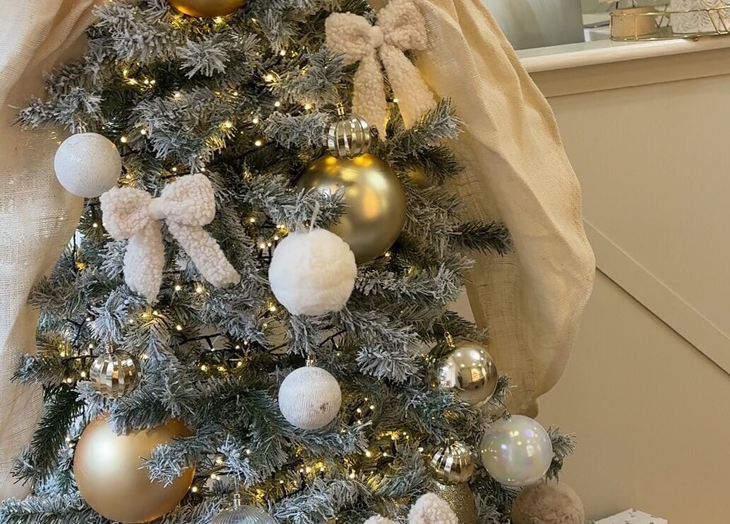 Festive Christmas tree at E Elegance & Co. in Paisley, Scotland, GB decorated with gold ornaments and twinkling lights.