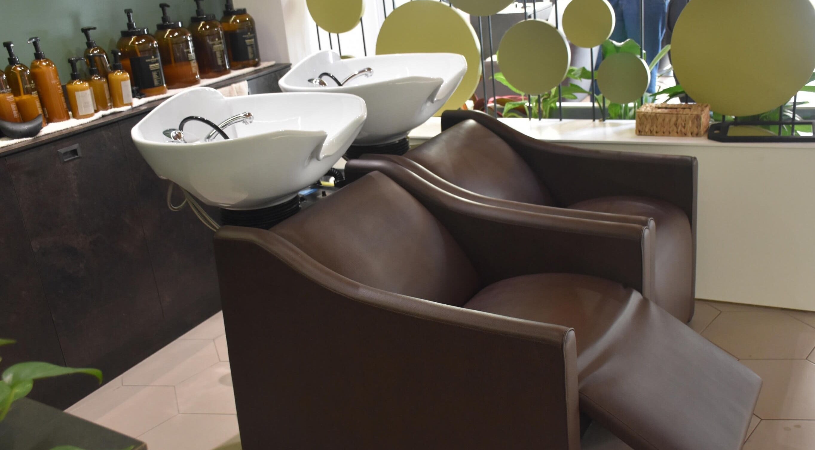 Area lavaggio moderna presso Salone Gala Rovigo, Rovigo, Veneto, IT, con poltrone marroni e lavabi bianchi.