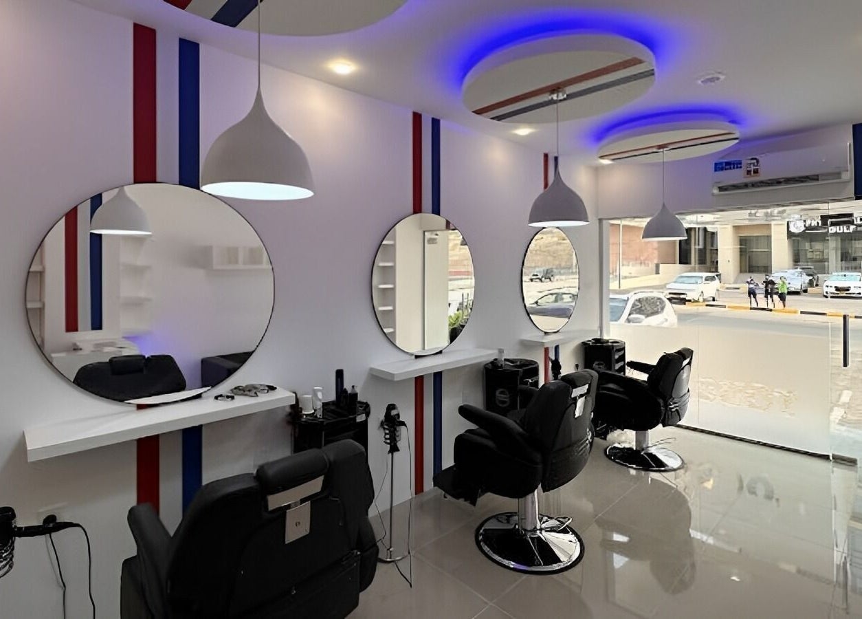 Chic salon interior at TOUCH UP - Wadi Kabir, Muscat, Oman showcasing modern black chairs and round mirrors.