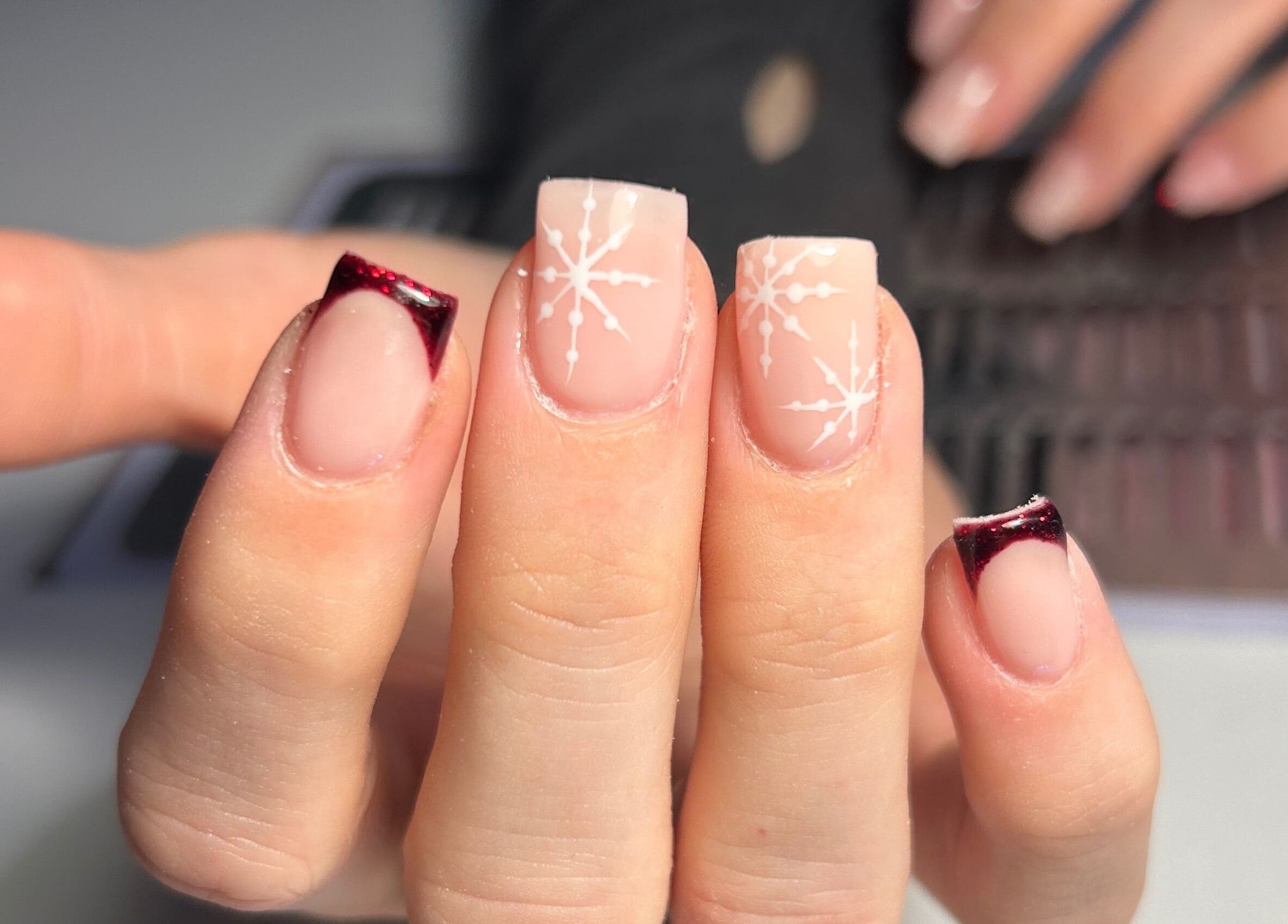Intricate nail art at The Beauty Q in Feering, England, GB, showcasing snowflake designs with red tips.