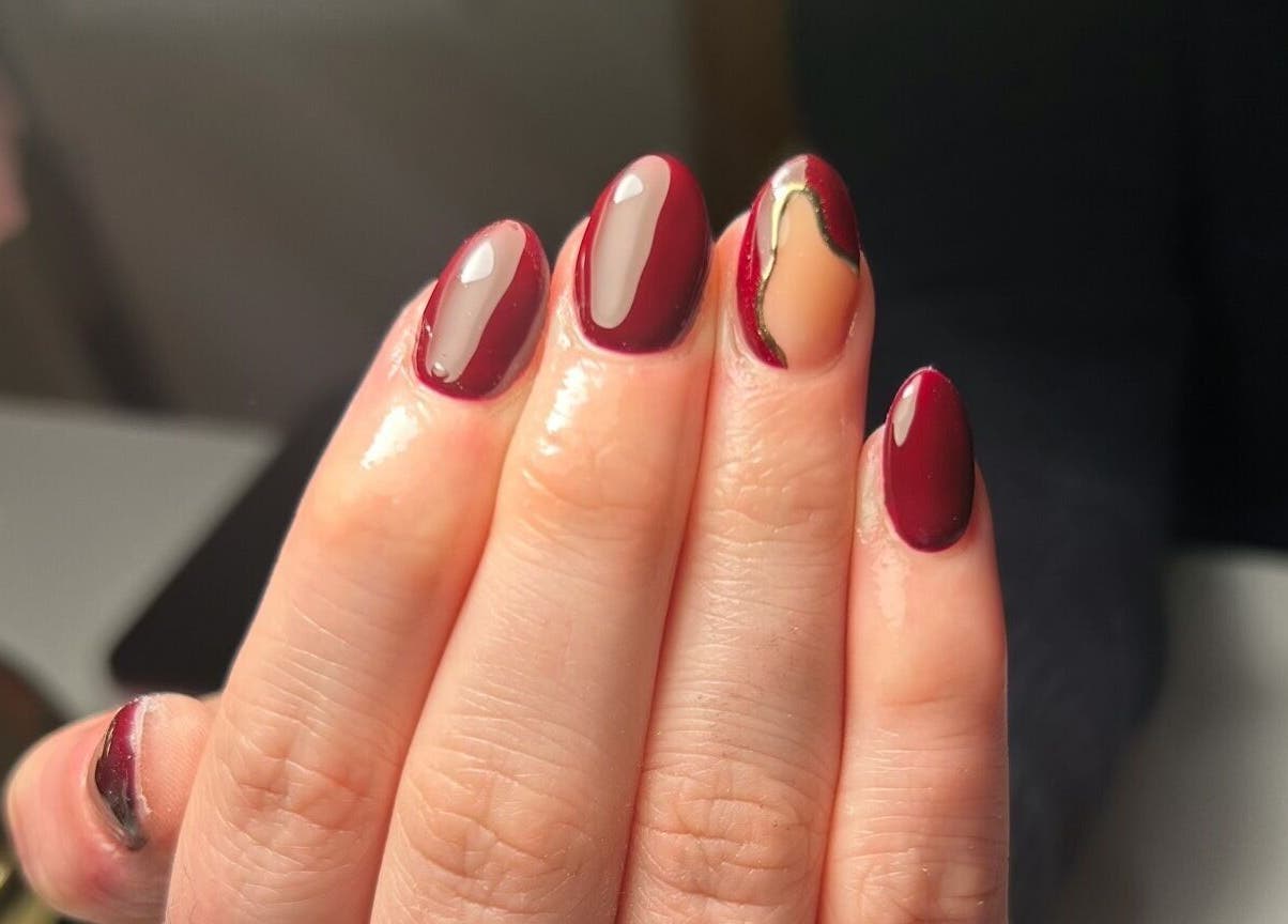 Stylish manicure at The Beauty Q in Feering, England, GB. Glossy red nails with artistic designs.