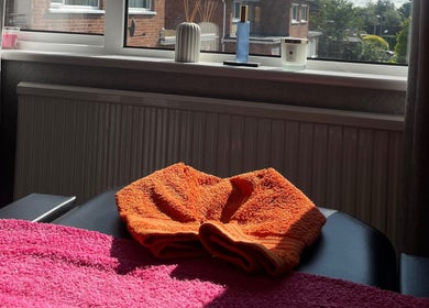 Sunlit massage table at The Body Club, Lisburn, Northern Ireland, GB, with vibrant towels and relaxing ambiance.