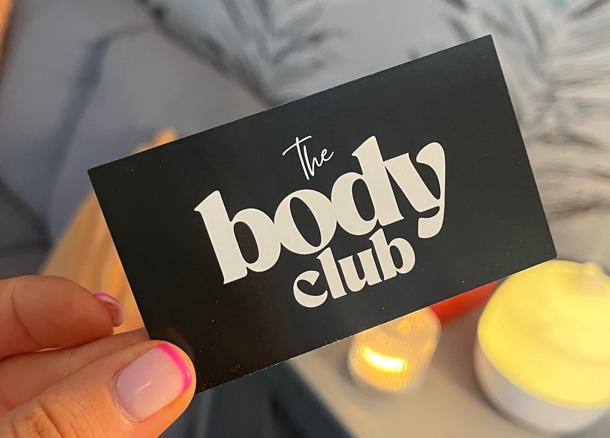 Close-up of a stylish card displaying 'The Body Club', Lisburn, Northern Ireland, GB with ambient lighting.
