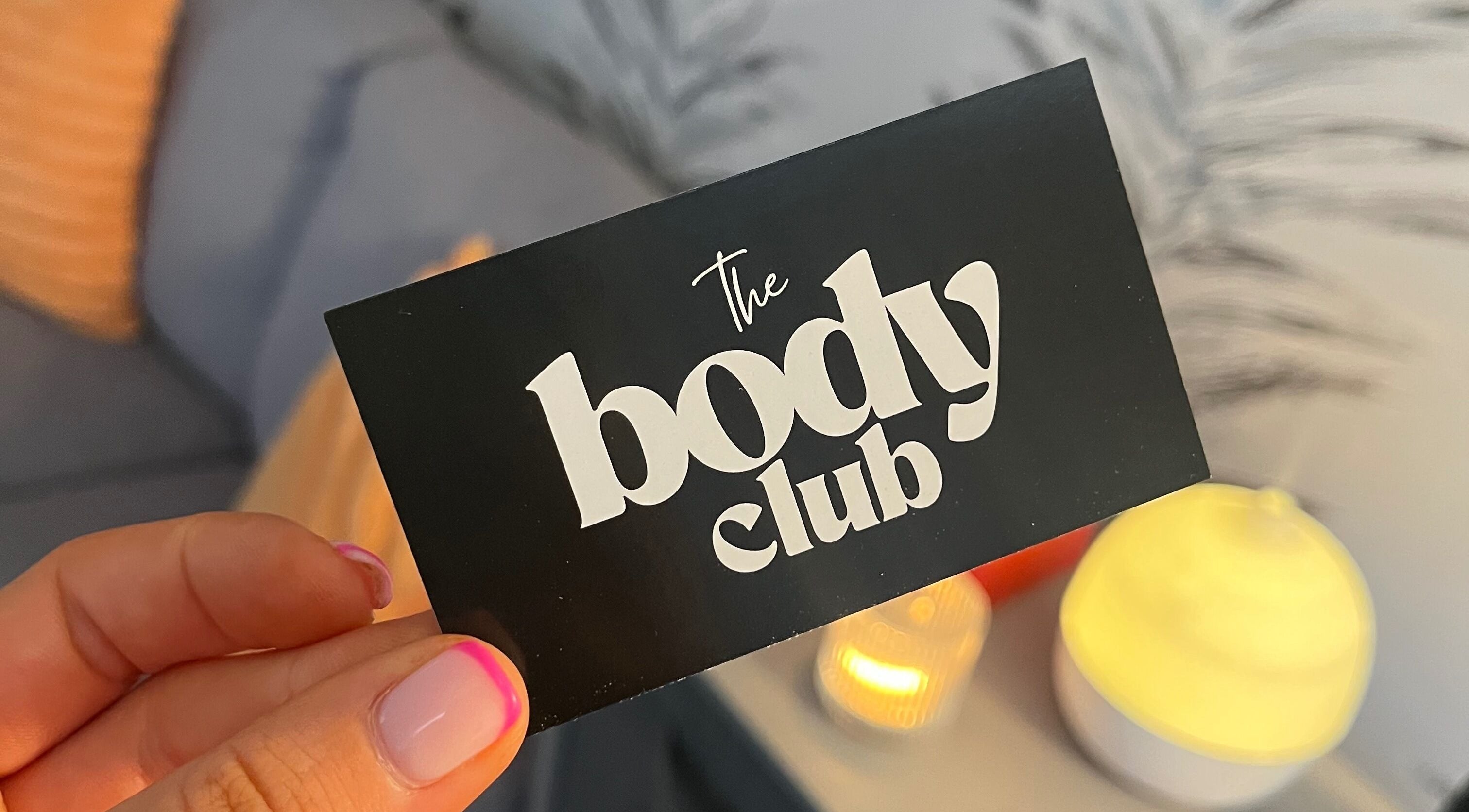 Close-up of a stylish card displaying 'The Body Club', Lisburn, Northern Ireland, GB with ambient lighting.